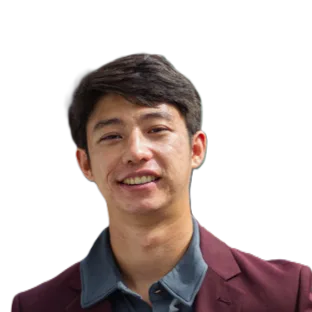 Head-and-shoulders portrait of a smiling man wearing a burgundy blazer and blue shirt.